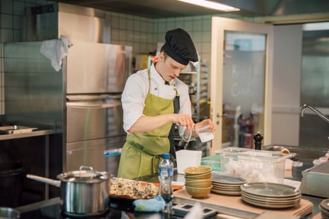 Koch in einer Restaurantküche bei der Zubereitung von Speisen.