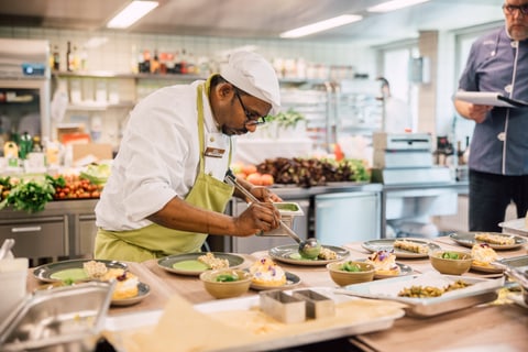 Chefkoch verfeinert Teller in einer professionellen Küche.