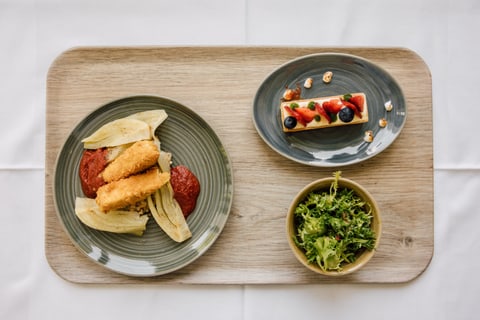 Holztablett mit frittierten Speisen, Kuchen und Salat.