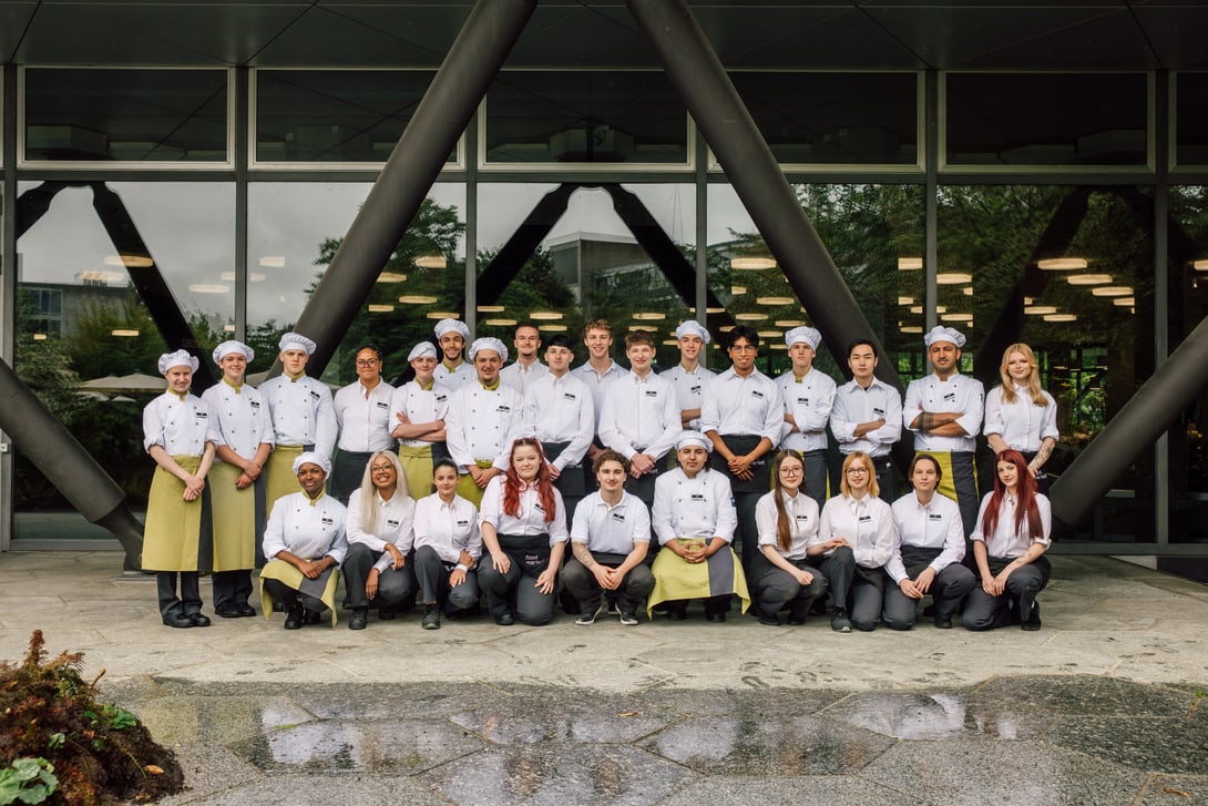 Gruppe von Menschen in Kochuniformen vor einem Gebäude.